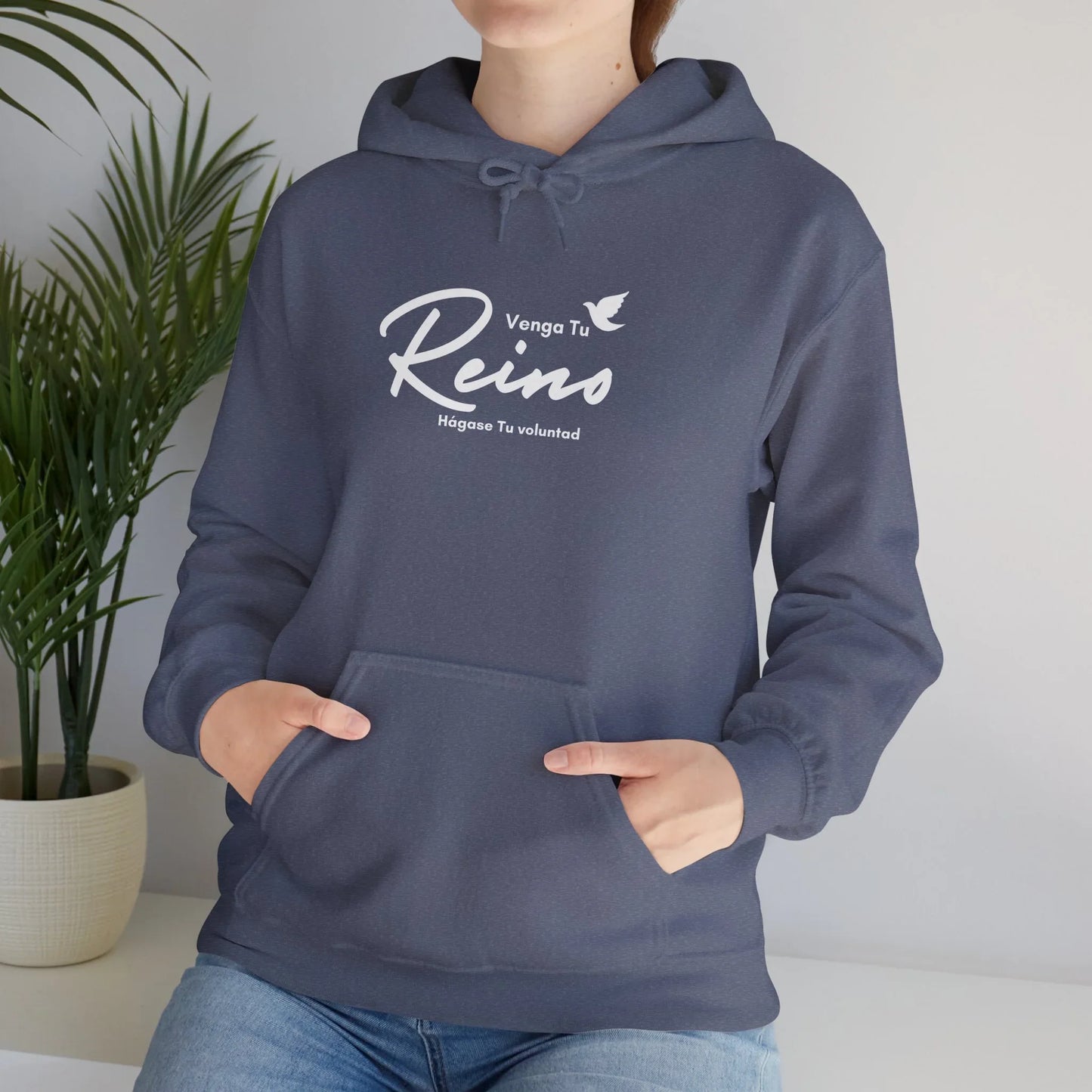 Woman wearing navy blue Christian hoodie with Spanish faith phrase and white dove design