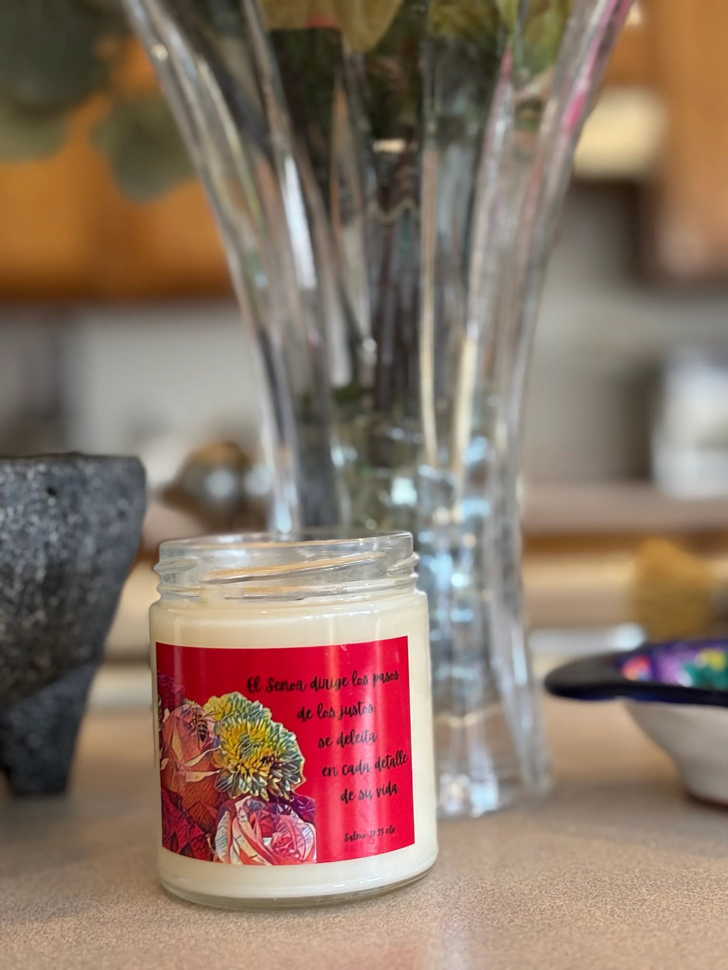 Christian scented candle with Spanish Scripture label, succulent plant, and books on windowsill