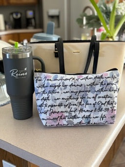 Woman holding Christian tote bag with Spanish Bible verse and colorful floral art