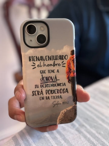 Christian phone case with Spanish Bible verse, mountain hiker design on wooden desk with accessories