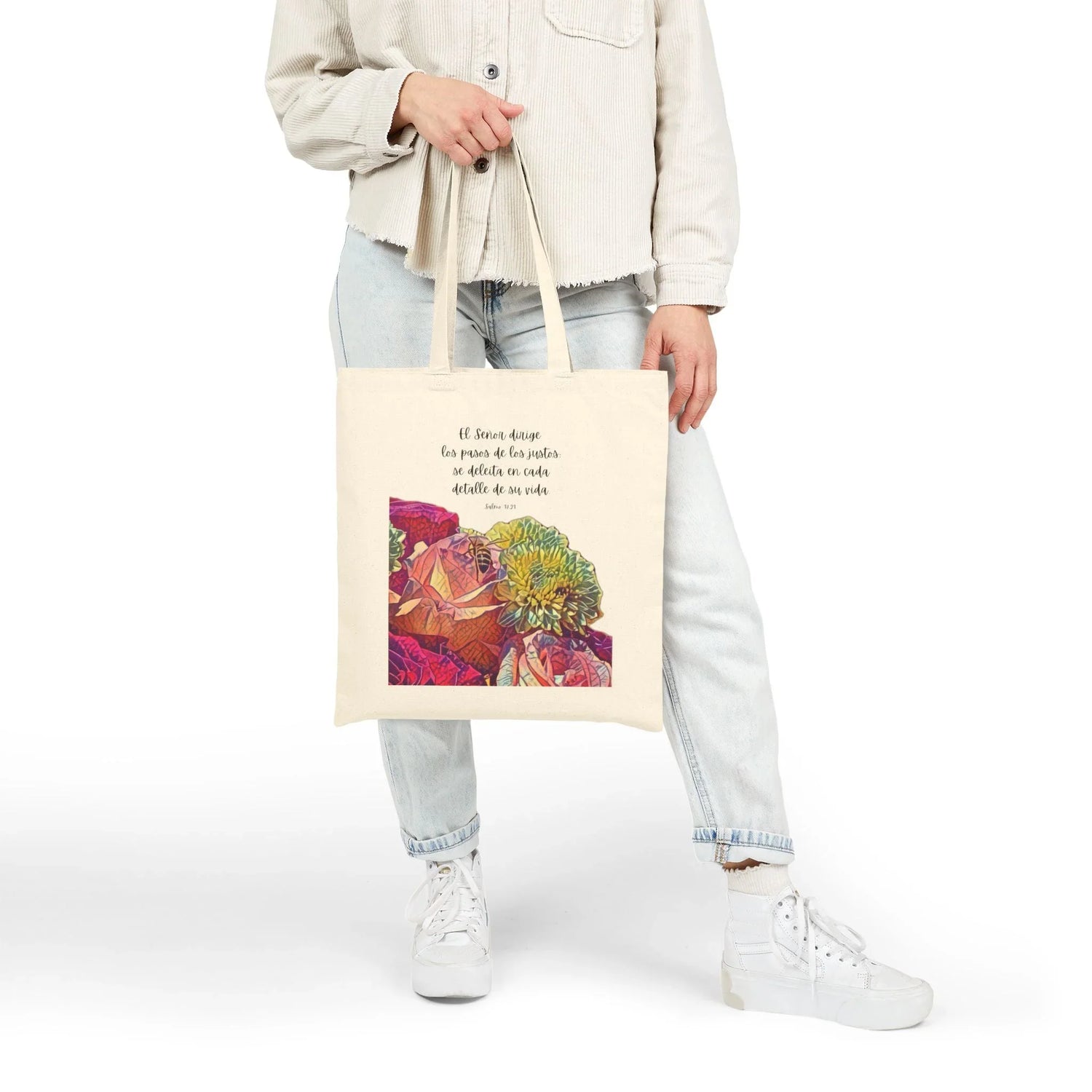 Woman holding Christian tote bag with Spanish Bible verse and colorful floral design