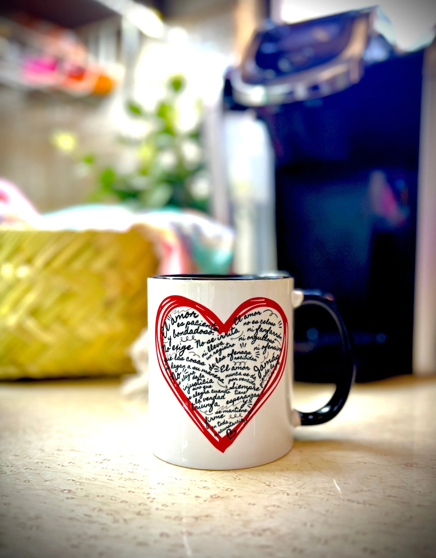 White ceramic mug with handwritten Spanish Bible verse in a red heart design, on kitchen counter