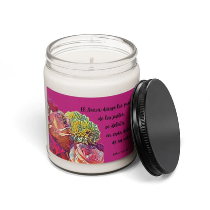 White glass candle jar with floral label and Spanish Bible verse, black lid beside jar.