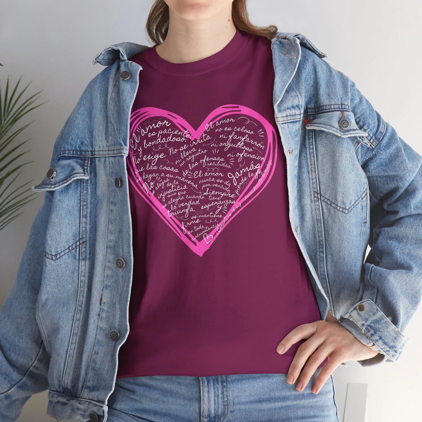 Woman wearing denim jacket over purple Christian t-shirt with Spanish Scripture heart design