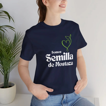 Woman wearing navy Christian t-shirt with 'Somos Semilla de Mostaza' and heart plant graphic.