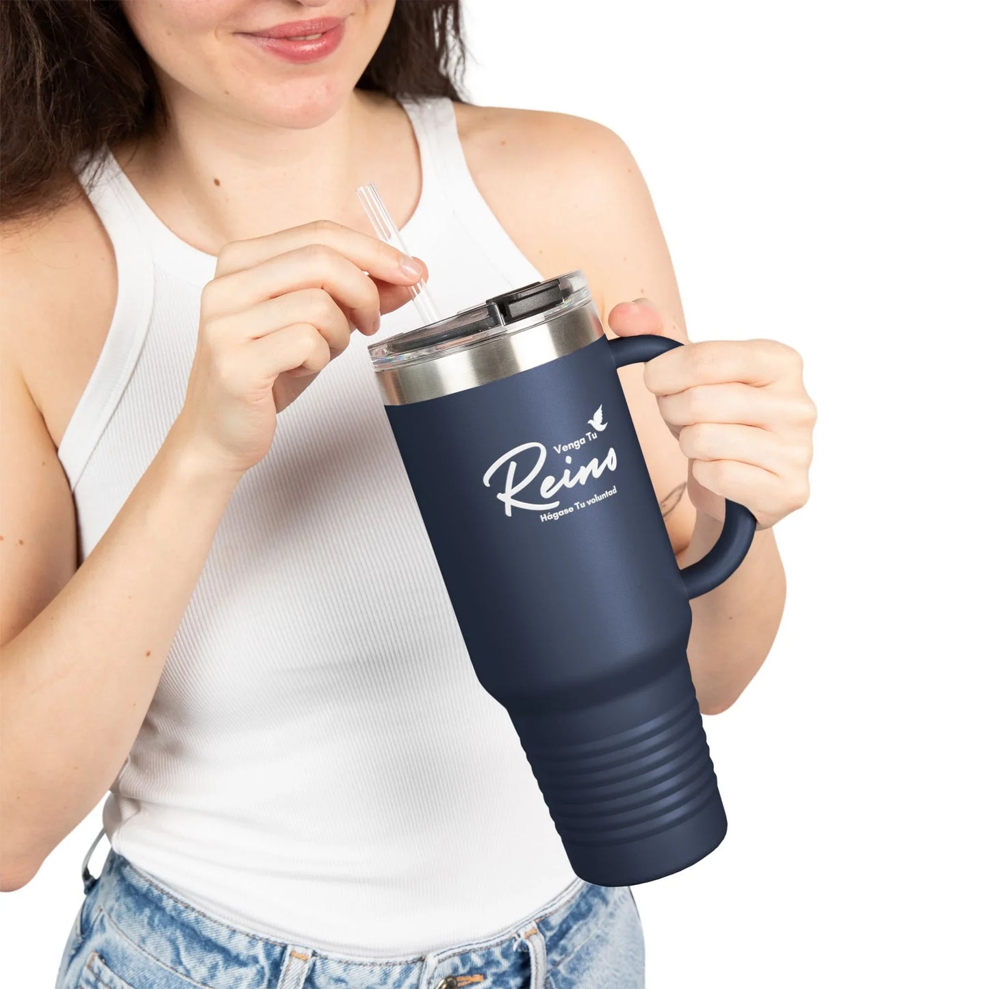 Woman in white tank top holding navy Christian travel mug with Spanish faith text