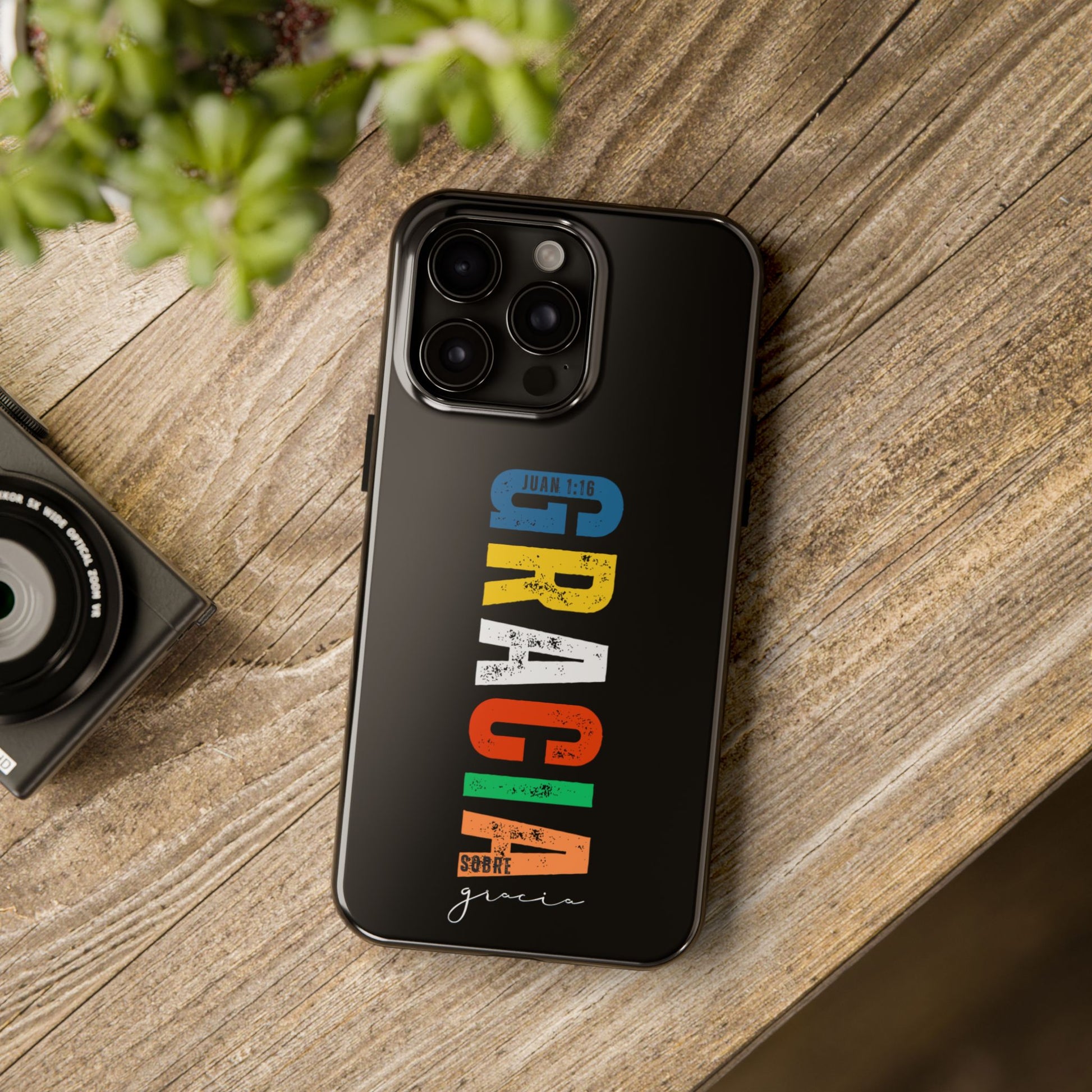 Black phone case with colorful Christian text design and Bible verse on wood table