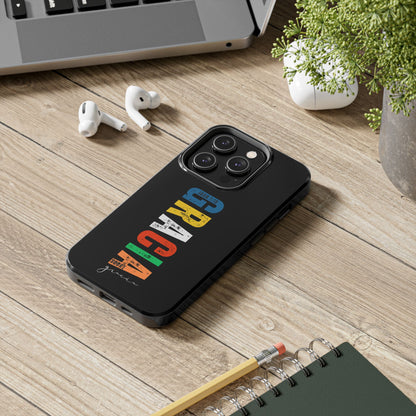 Black phone case with colorful 'GRACIA' text and Christian message on wooden desk
