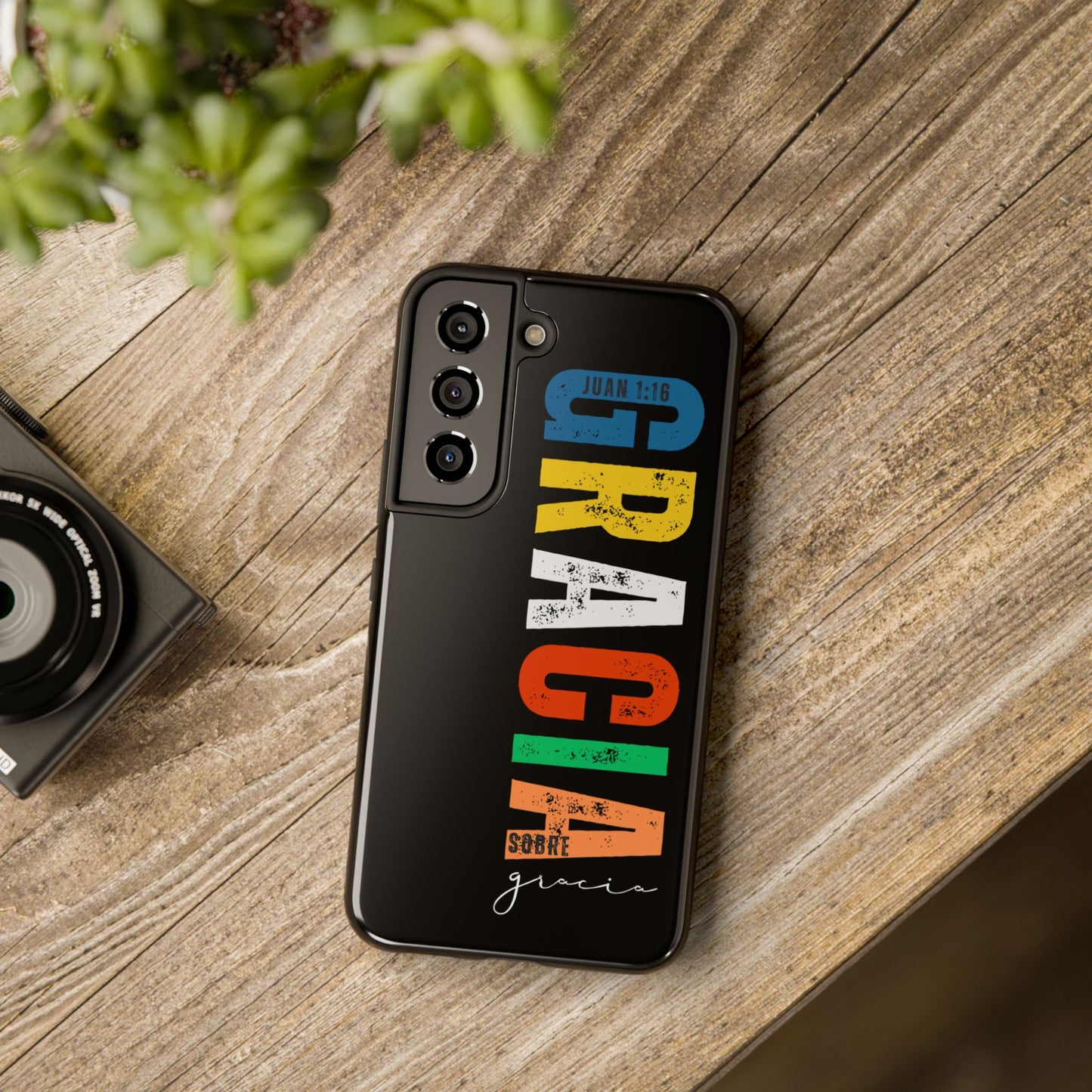 Colorful Christian phone case with Juan 1:16 verse on wooden table, modern faith design