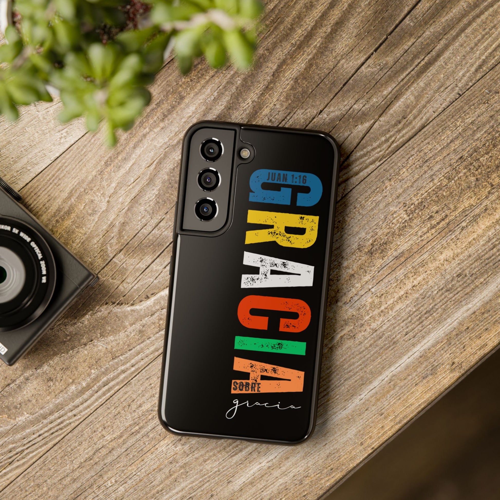 Colorful Christian phone case with Juan 1:16 verse on wooden table, modern faith design