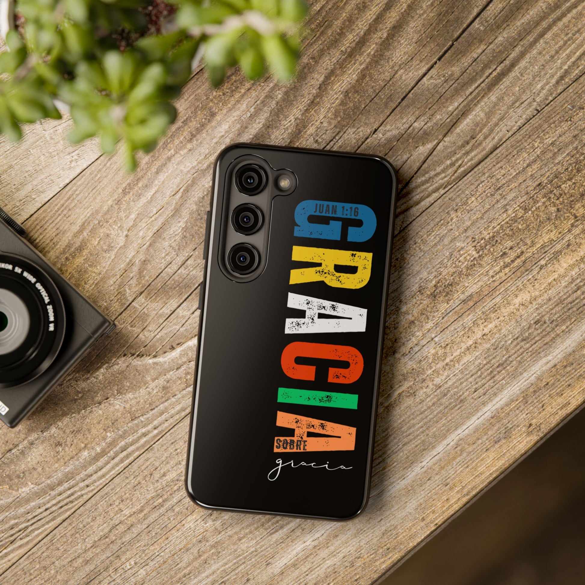 Black phone case with colorful Christian faith message in Spanish and Bible verse, on wood table