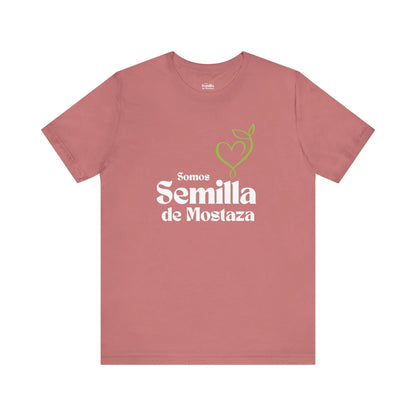 Pink Christian t-shirt with 'Somos Semilla de Mostaza' and green heart-shaped sprout graphic.