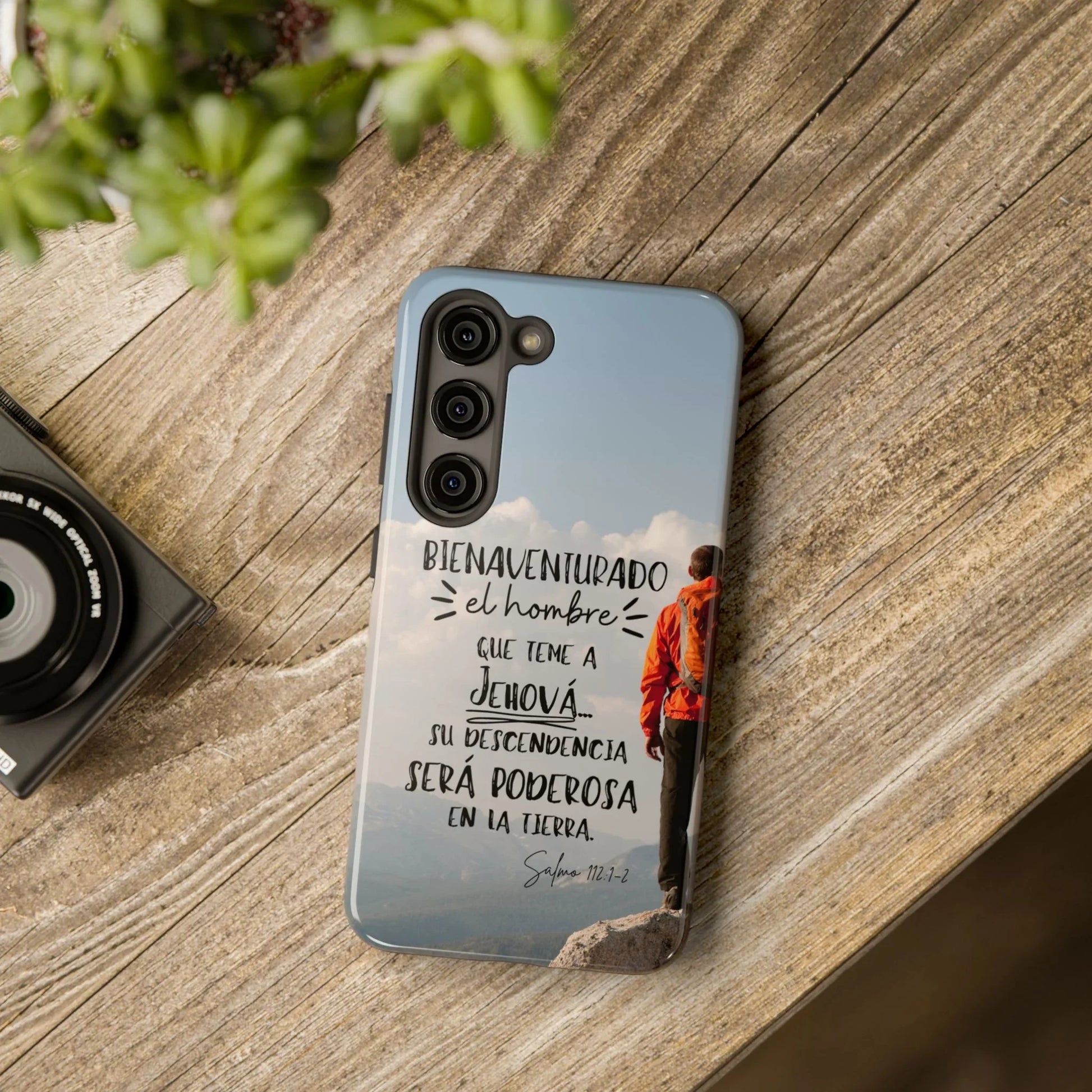 Christian phone case with Psalm 112:1-2 in Spanish, mountain hiker design on wood table