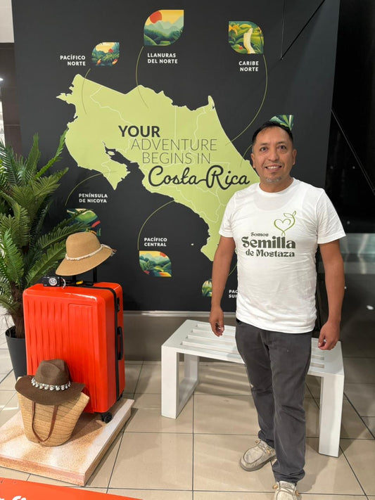 Man wearing Christian t-shirt stands by luggage at Costa Rica travel display