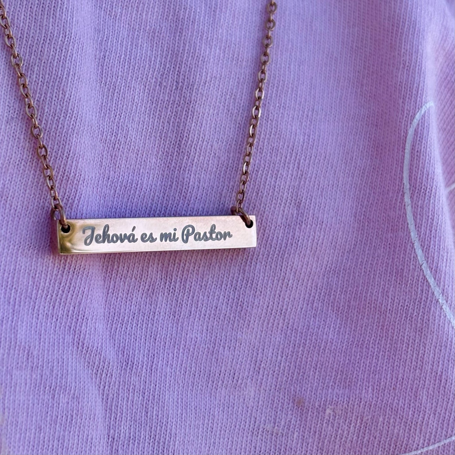 Gold bar necklace with 'Jehová es mi Pastor' engraved, worn on a lavender shirt.