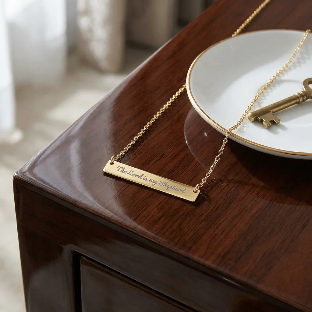 Gold bar necklace engraved with 'The Lord is my Shepherd' on wooden table, Christian jewelry