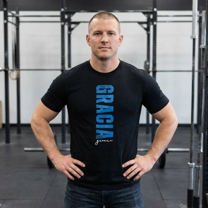 Man in gym wearing black Christian t-shirt with 'GRACIA' and Scripture design