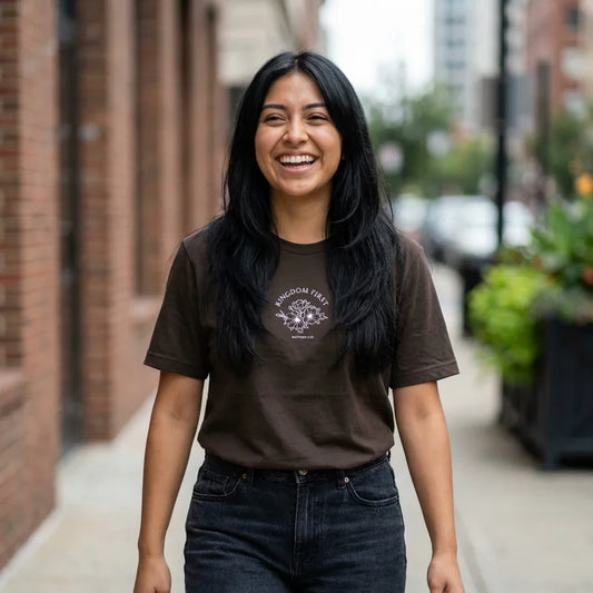 Smiling woman wearing dark Christian graphic t-shirt with 'Kingdom First Matthew 6:33' text outdoors