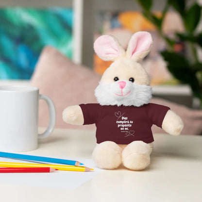 Plush bunny with maroon Christian shirt, Spanish faith quote, on a desk with mug and pencils.