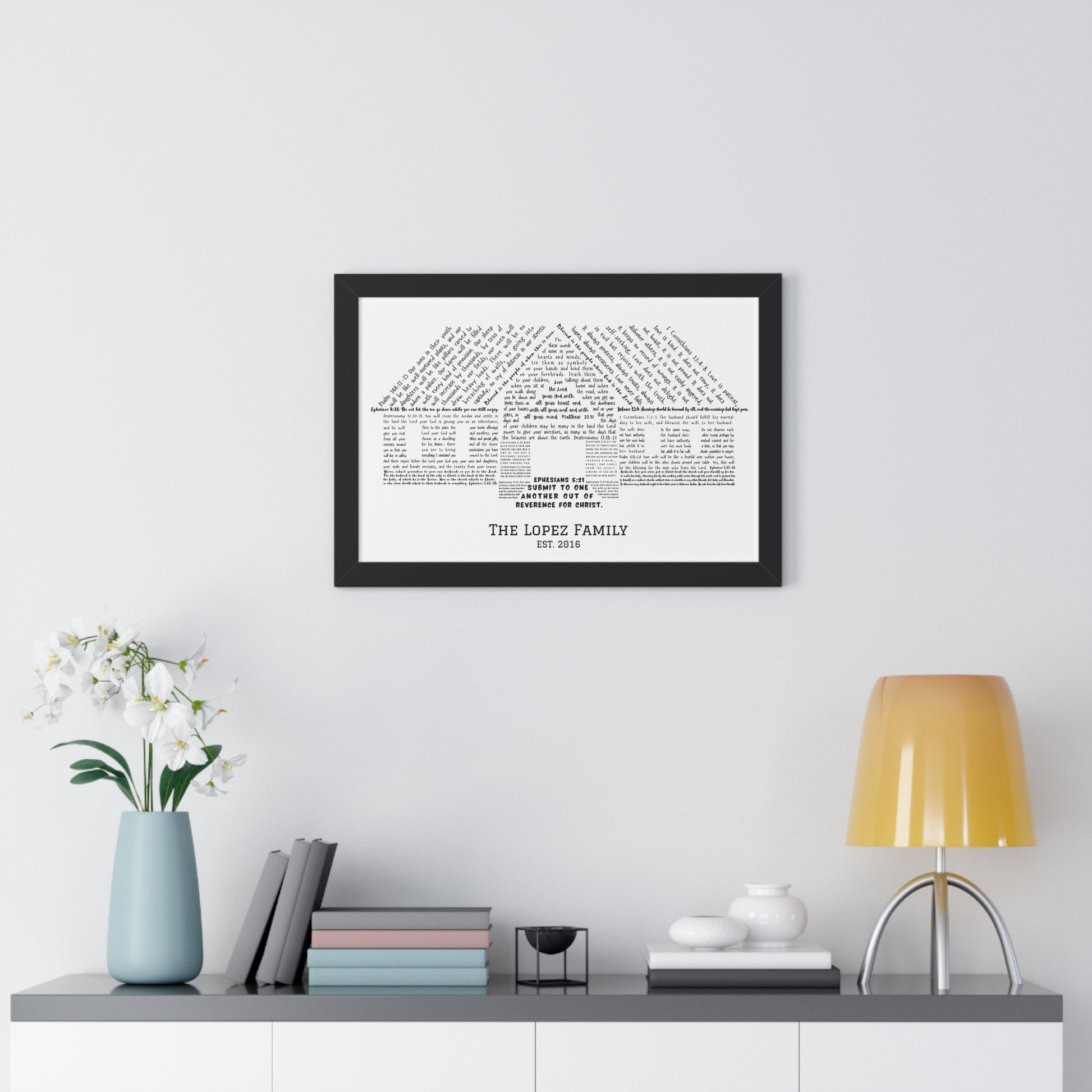 Framed custom family name Christian wall art shaped like a house, on modern home decor shelf.