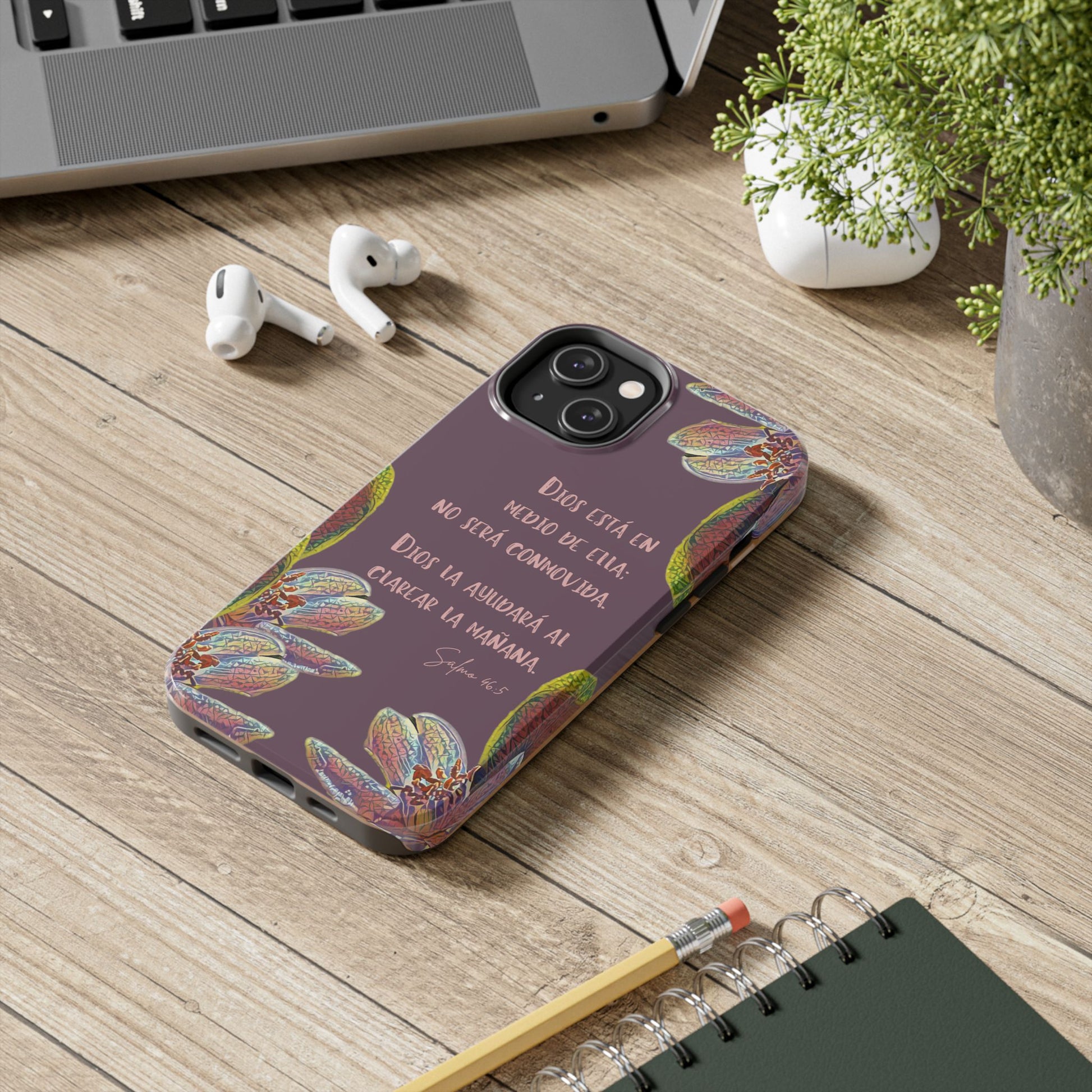 Purple Christian phone case with Spanish Scripture and floral design on a desk with accessories