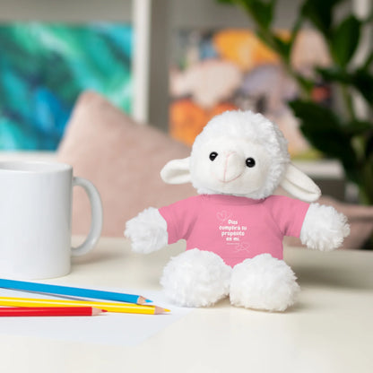 Plush lamb toy with Christian message on pink shirt, beside mug and colored pencils