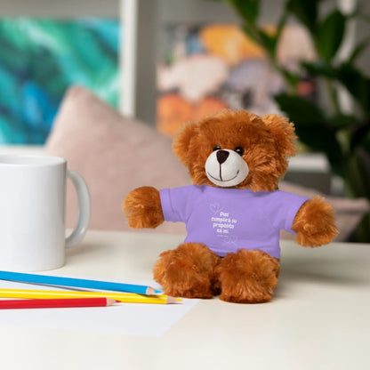 Plush teddy bear in a purple Christian T-shirt with Spanish text on a desk with pencils and mug.