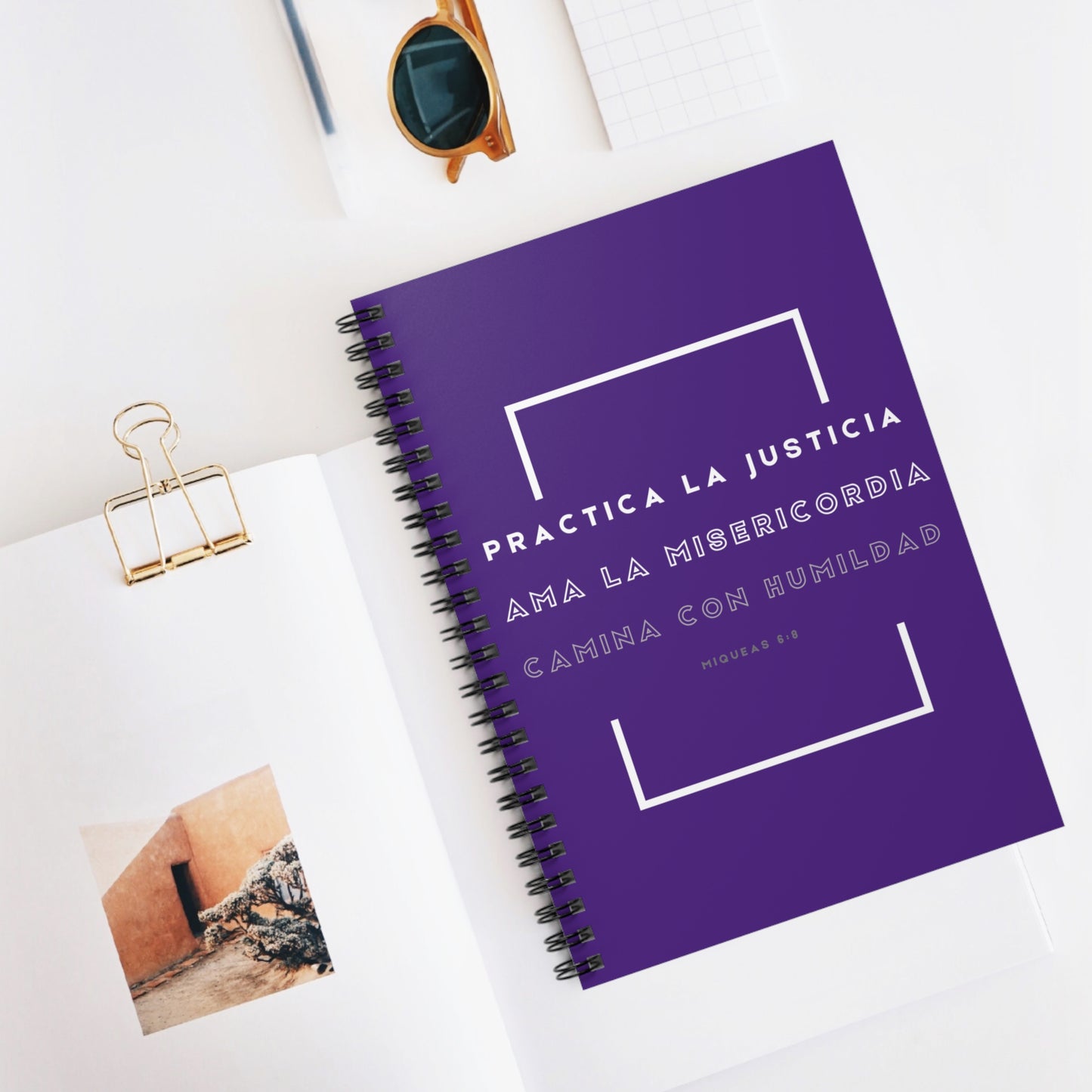 Purple Christian spiral notebook with Spanish Bible verse on white desk, modern stationery