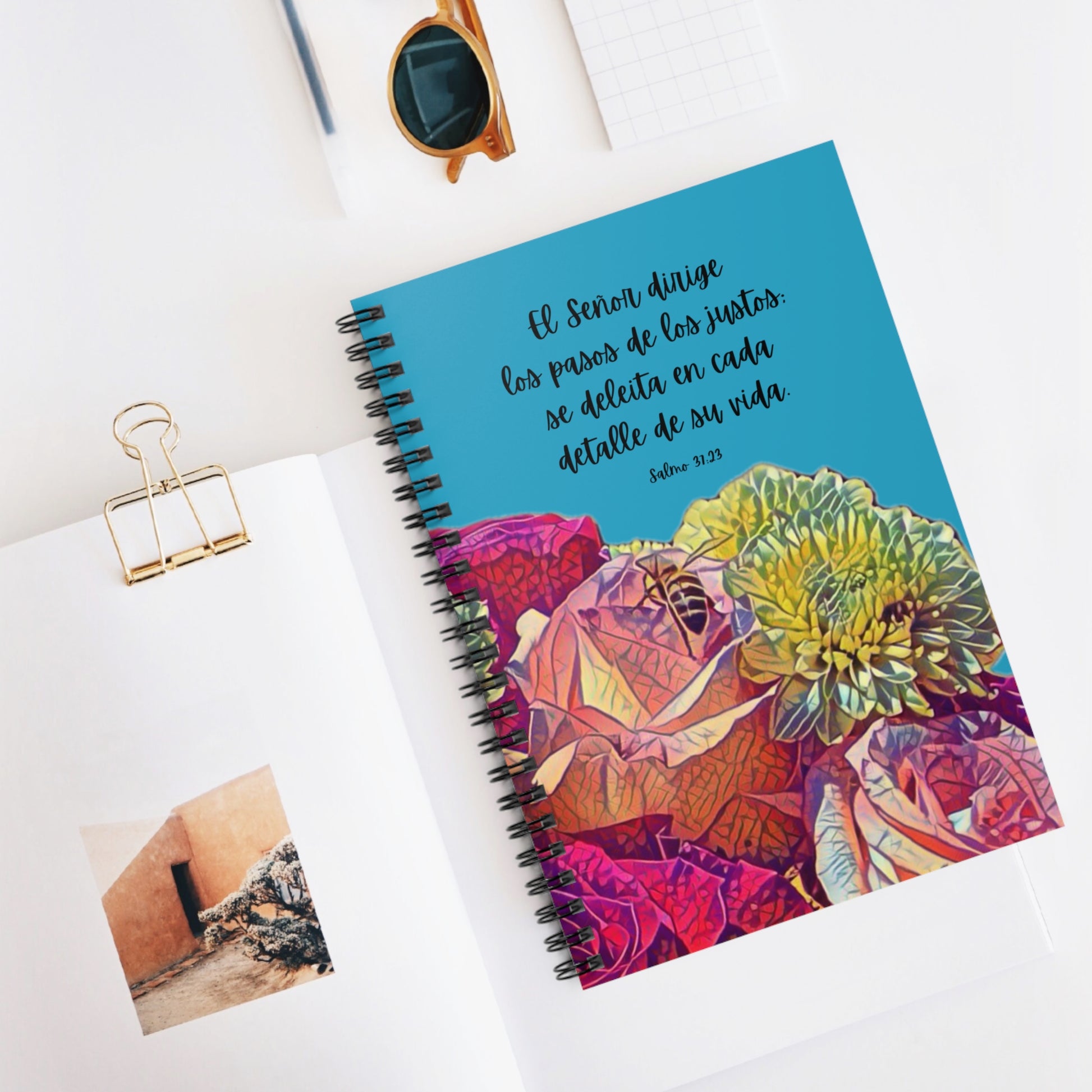 Christian floral notebook with Spanish Bible verse, spiral bound, on a white desk