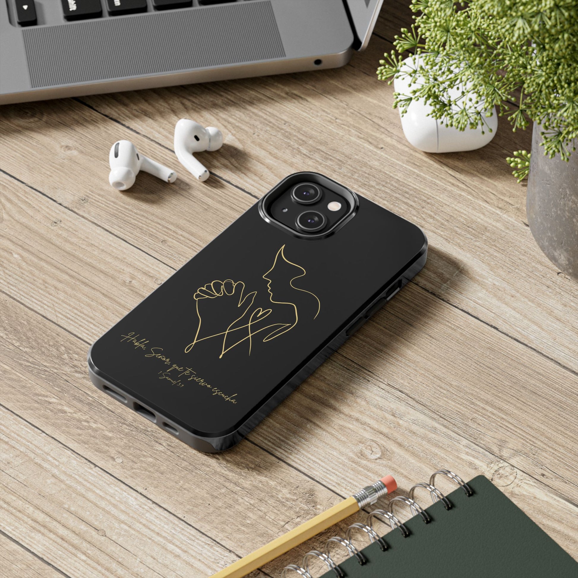 Black Christian phone case with gold praying hands line art, inspirational text, on a desk