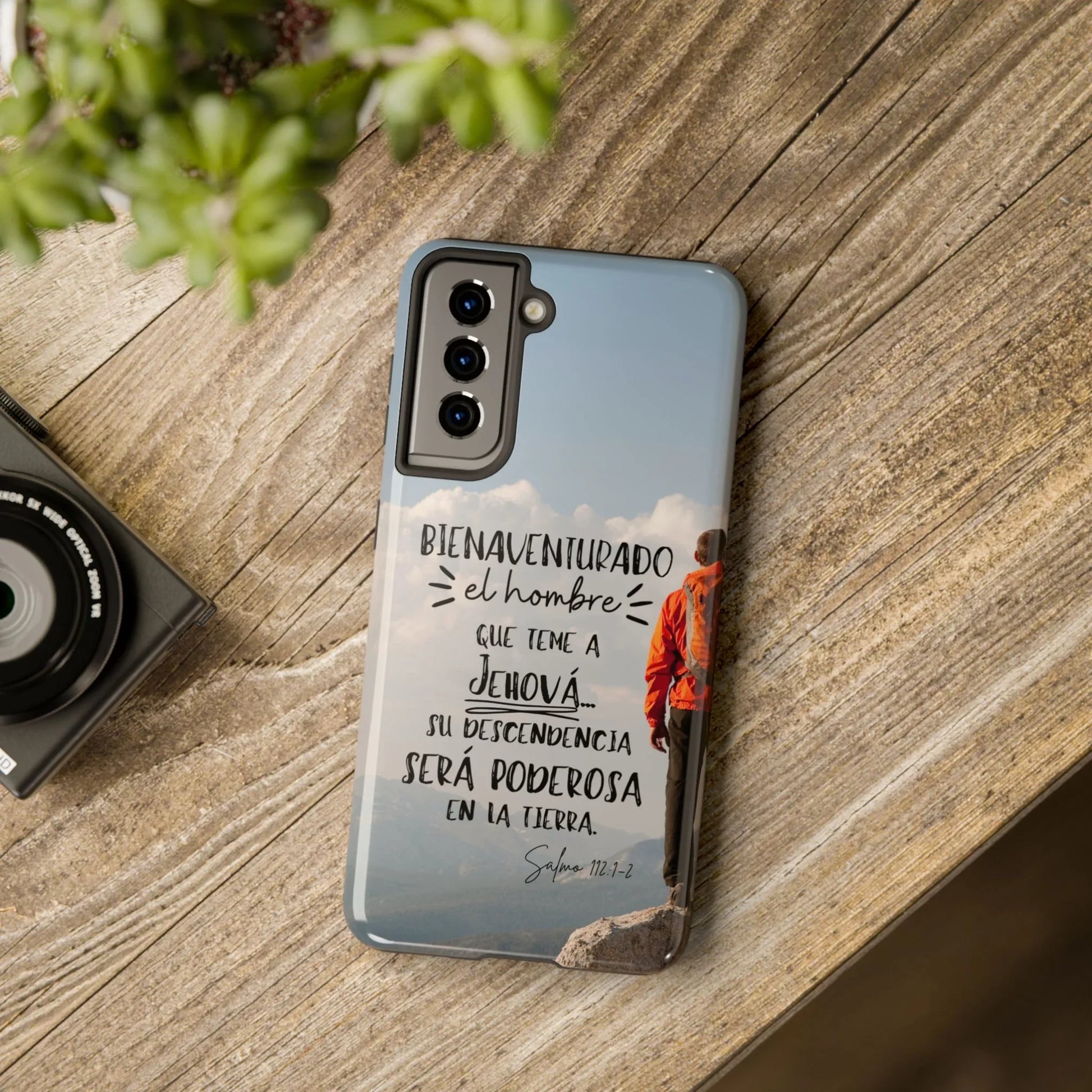 Christian phone case with Spanish Bible verse, mountain view, on rustic wooden table