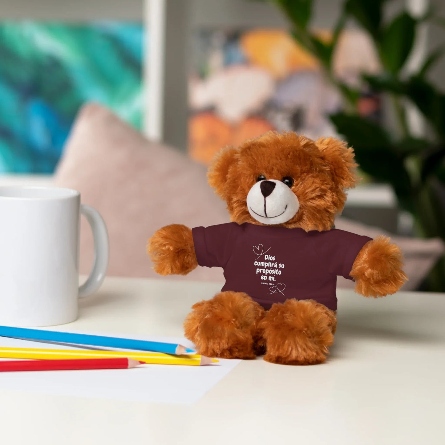 Christian teddy bear plush with Spanish Bible verse shirt, on desk with pencils and mug