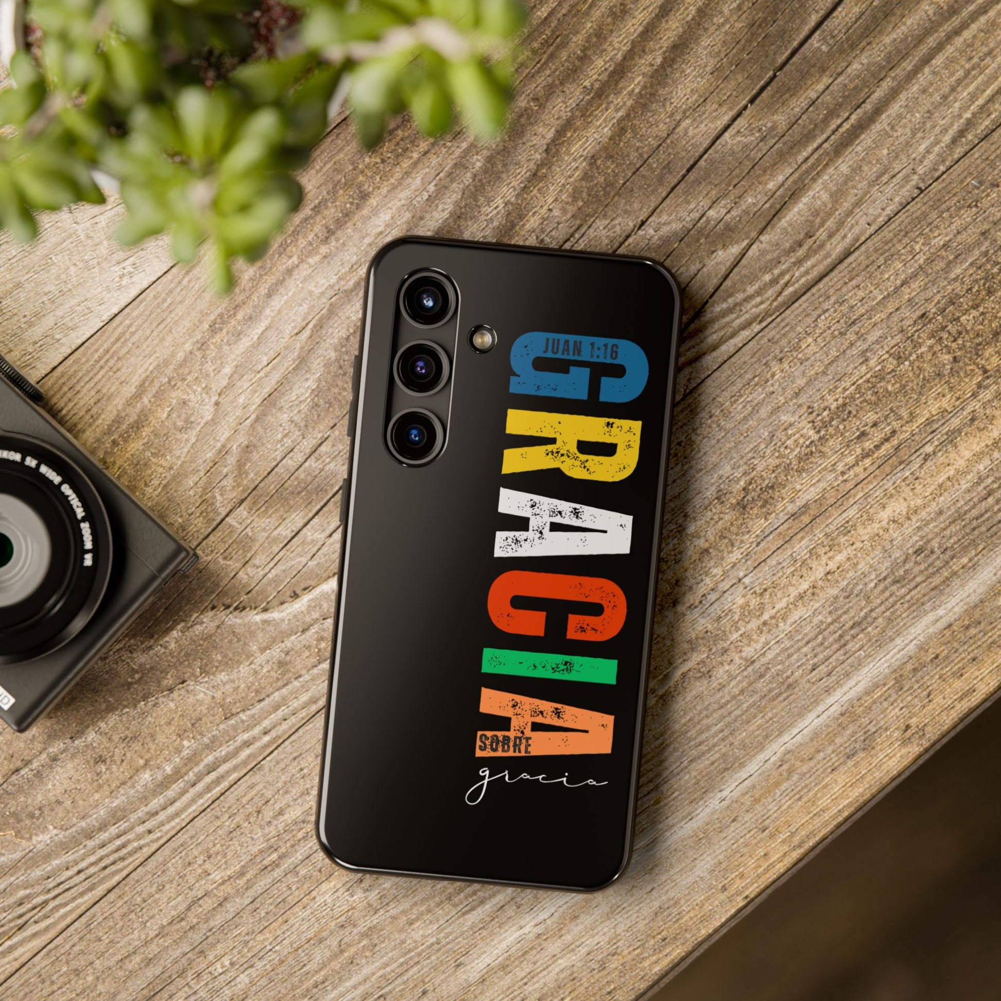Christian phone case with colorful text 'Gracia sobre gracia' and John 1:16 verse on wood table