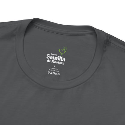 Closeup of dark gray Christian t-shirt label with Semilla de Mostaza text and green sprout graphic
