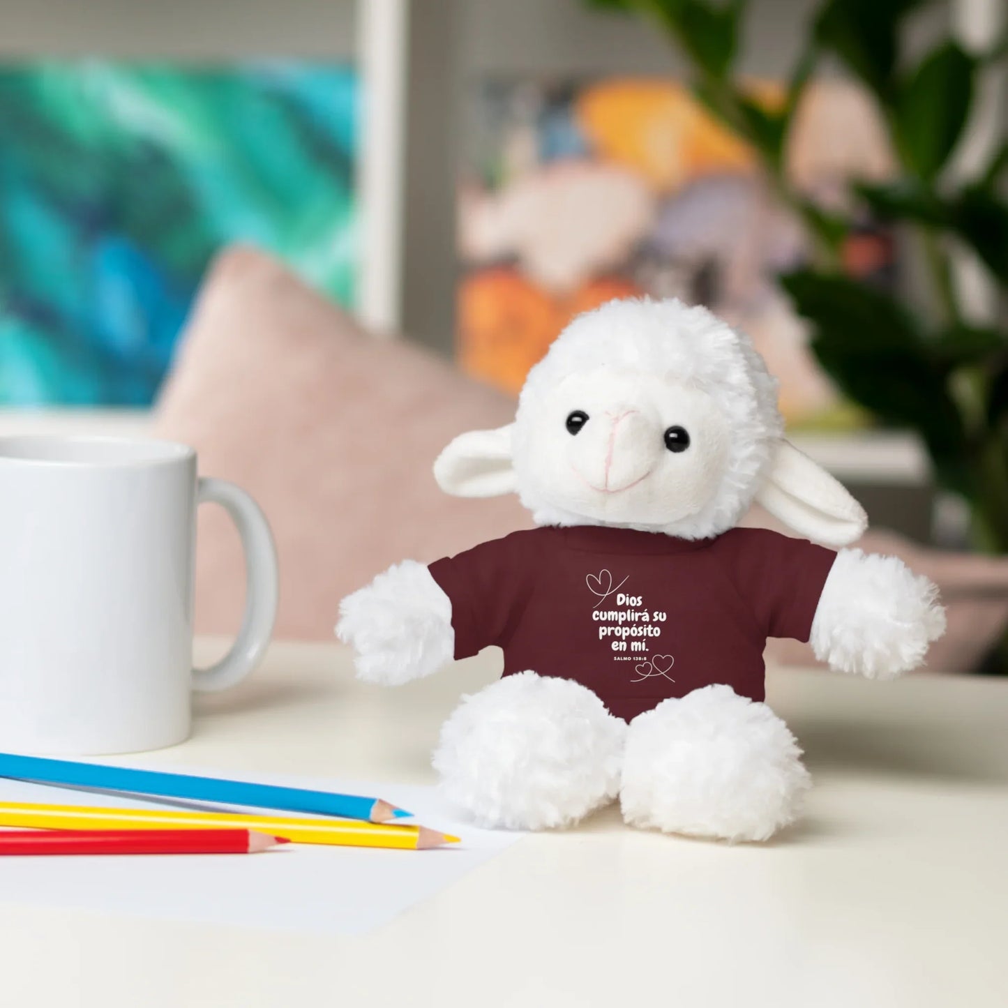 Plush lamb toy with Christian shirt and Spanish inspirational message on desk with mug and pencils