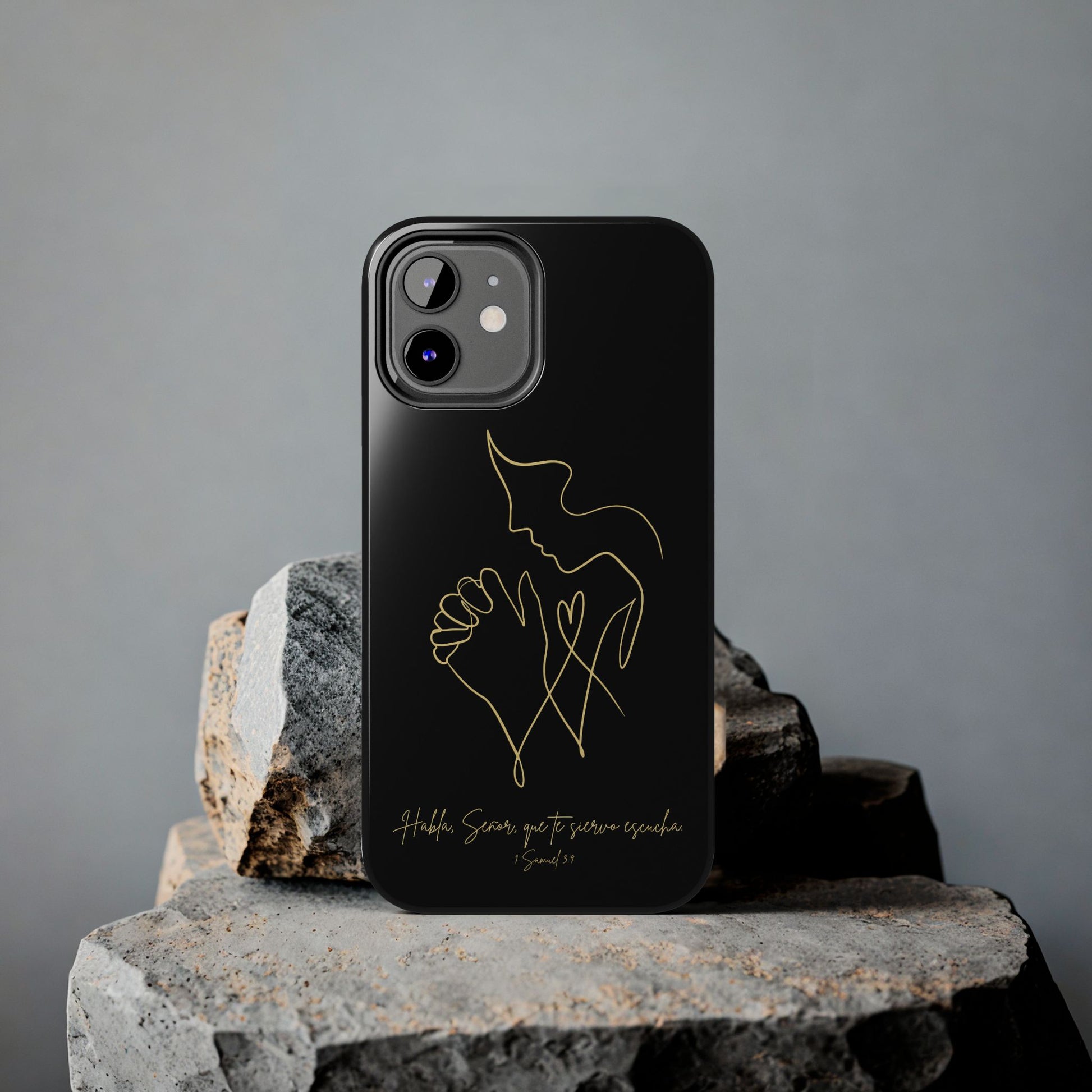 Black phone case with gold outline of praying hands and scripture, displayed on stone.