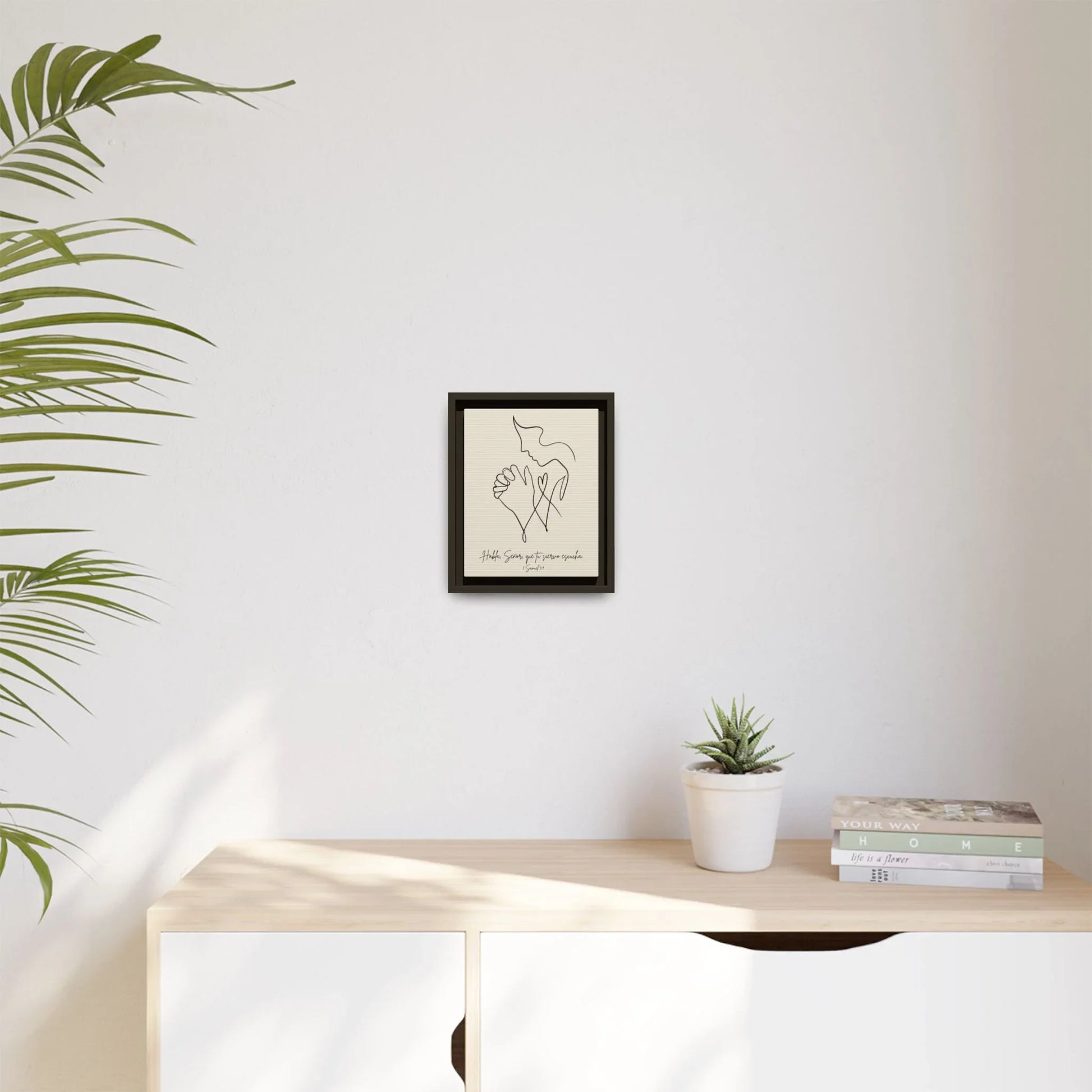 Minimalist Christian wall art with hand and dove in black frame, decor on light wall above modern console.