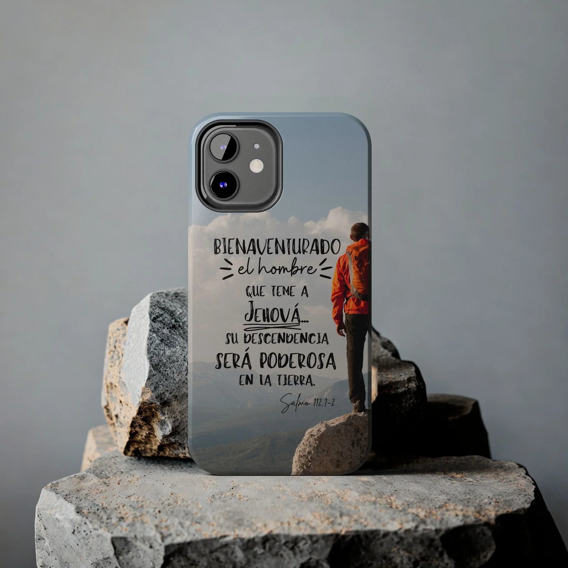 Christian phone case with Spanish Bible verse, hiker design, displayed on stone background